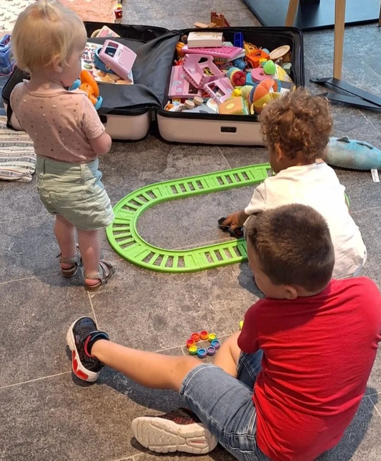 Mother plays with her baby and son on the floor