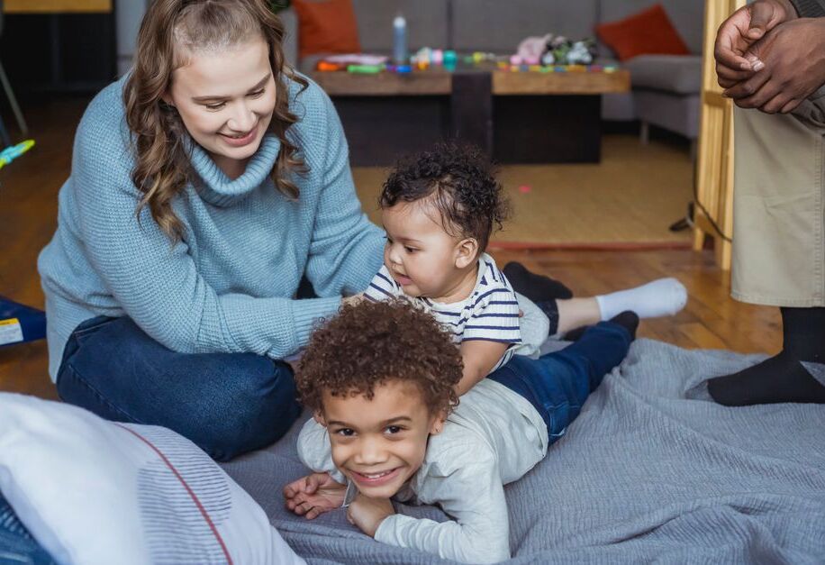 Moeder speelt met haar baby en zoon op de vloer